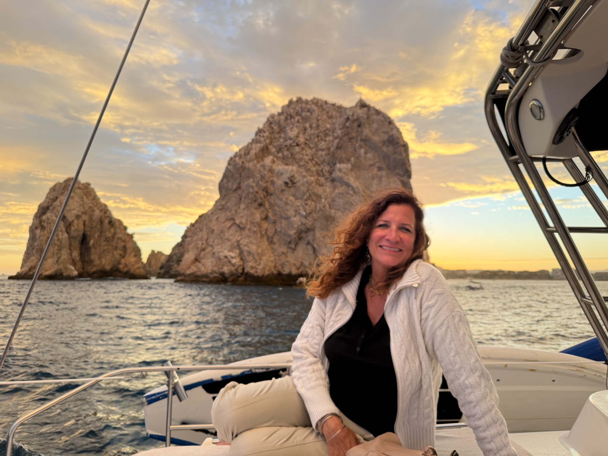 Beth enjoying a sunset boat ride beside dramatic coastal rocks